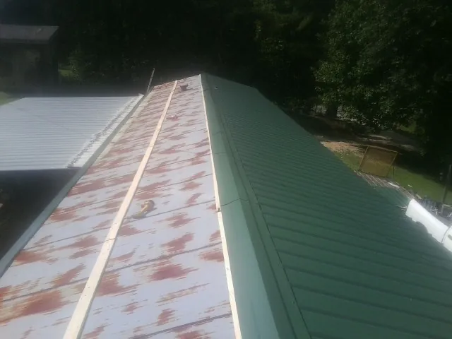 Old rusted panels beside newly installed green metal roofing — Wind Damage Roof Repair by Roofing Brothers in Debary