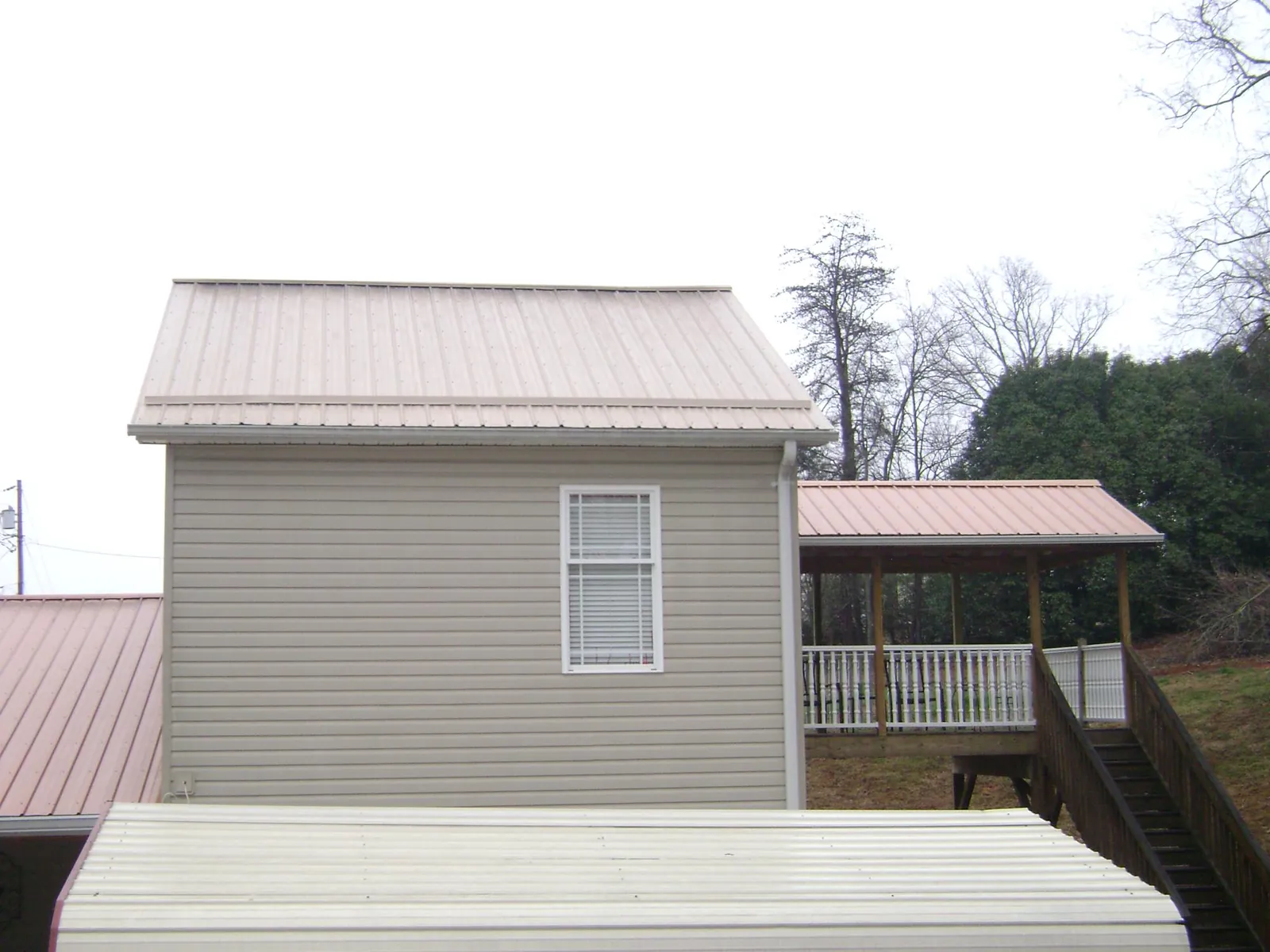 Tan metal roofs on a two story addition and attached porch, from a Roof Replacement job in Debary