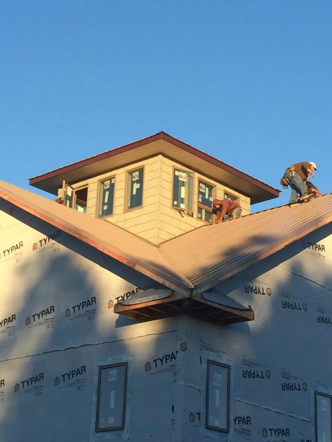 Roofers working around a rooftop cupola on a new metal roof at sunset — Roof Waterproofing in Debary by Roofing Brothers
